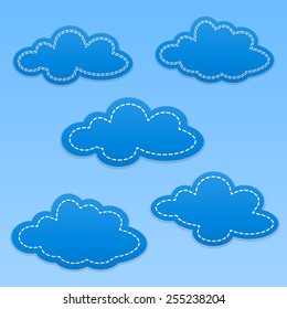 Set of cloud paper tags. Blue clouds with white dotted lines. Blue sky.