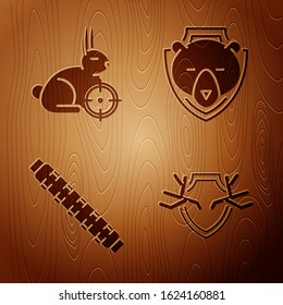 Set Deer antlers on shield, Hunt on rabbit with crosshairs, Hunting cartridge belt with cartridges and Bear head on shield on wooden background. Vector