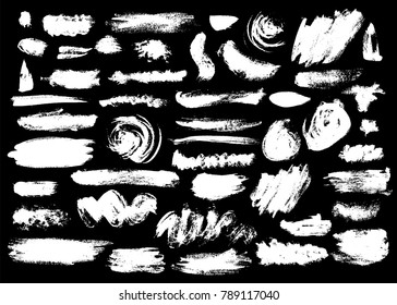Set of different white brush strokes on black background. Stripes, blobs, circles and shaggy shapes.