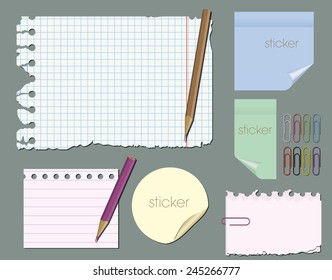set of empty pieces of paper with pencils and paper clips on a gray background