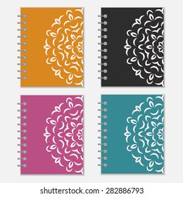 Set of four colorful notebook covers with flower design. Orange, black, purple and blue wrappers with ornate pattern