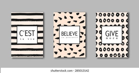 A set of hand drawn brushstrokes designs. Black paint patterns on pastel pink background with text in black and white. "C'est la Vie" (French for "That's Life"), "Believe in Yourself", "Give More".