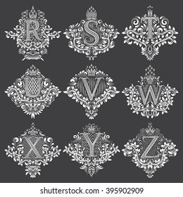 Set of heraldic monograms in coats of arms form. White floral decorative stamps on black. Isolated tattoo labels in vintage baroque style.