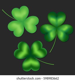 Set of isolated green clover leaves on a dark background.

