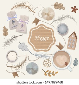 A set of items for a cozy evening with a sachet, candles, a cup of coffee with a coffee foam heart, feathers and a Hygge unifying inscription