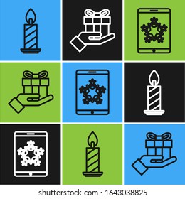 Set line Burning candle in candlestick, Christmas on smartphone and snowflake and Gift box in hand icon. Vector