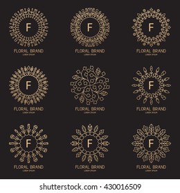 Set of logos in trendy linear style. Golden labels with frame from floral ornament. Logotypes for fashion, beauty, spa, hotel and jewelry industry.