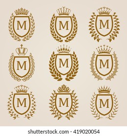 Set of luxury golden shields with laurel wreaths, crowns. Royal heraldic elements, emblems, icons, symbols, labels, badges, blazons, monograms for web, page design. Vector illustration EPS 8.