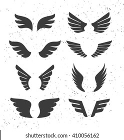 Set of monochrome open wings for badges and signs. Vector symbolic black wings isolated on white. Silhouettes of stylized flapping wings.