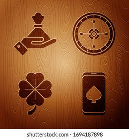 Set Online poker table game, Hand holding money bag, Four leaf clover and Casino roulette wheel on wooden background. Vector