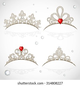 Set openwork jewelry tiaras with diamonds and faceted red stones in a heart shape on white background