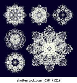 Set of ornamental rosettes-snowflakes on dark background