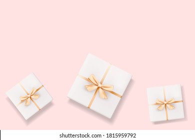 Set of realistic 3D white gift boxes with golden bow isolated on pink.