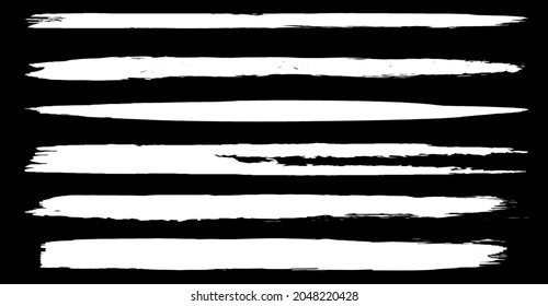 A set of vector brushes in grunge style. White paint strokes with a dry brush on a black background