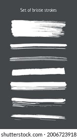 A set of white bristle strokes on a dark gray background. Vector design elements. White isolated on a dark background