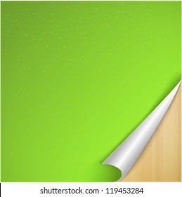 Sheet of Green Paper with Curved Corner on wooden background