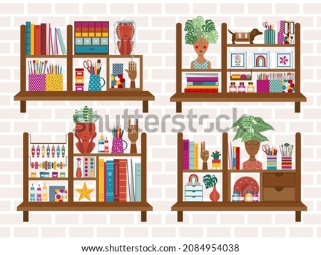 Shelf decor in creative home art studio. Artistic bookshelves with painting, drawing and hobby craft supplies, plants in face planters pots, books, stationary, wooden hands and decorative elements.
