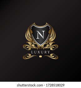 Shield Logo In Gold Color With Letter N Logo. Elegance Logo Vector Template Made Of Wide Silver Alphabet Font On Shield Frame Ornate Style.
