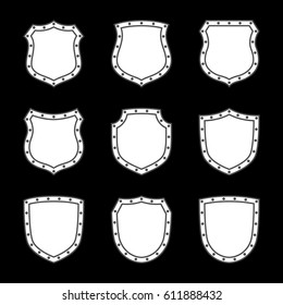 Shield shape icons set. White label signs isolated on black background. Symbol of protection, arms, security, safety. Flat retro style design. Element vintage heraldic emblem Vector illustration