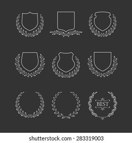 Shields and laurel wreaths icons set. White line on a black background.	