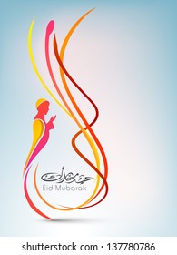 Shiny Arabic Islamic calligraphic text Eid Mubarak with illustration of a Muslim person in tradition outfits reading Namaj ( Islamic Prayer) on blue background.