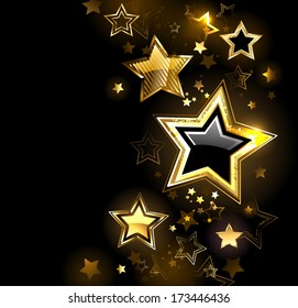 Shiny gold star with small stars on black background.