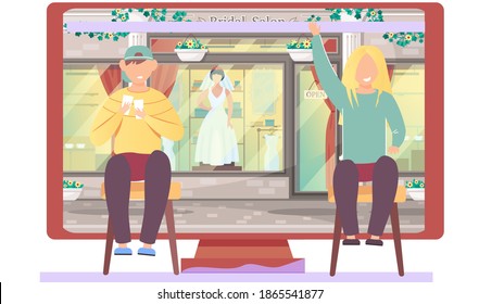 Shop of goods and festive clothing. Guy and a girl are sitting near the computer and talking. Bridal boutique on the background. Man sits on a chair and plays with cards. Woman happily raises her hand