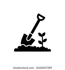 Shovel with Curved Blade Partially Embedded in Soil Next to Small Plant