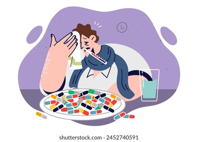 Sick man with high fever drinks lot of pills to get rid of flu symptoms, sits at table with thermometer in mouth. Sick guy fell victim to new strain of pandemic. Causing fever and chills