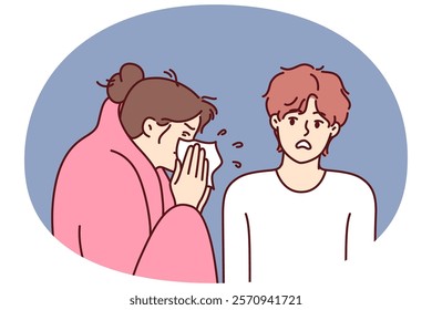 Sick woman sneezes standing near guy afraid of contracting dangerous flu or cold. Sick girl with handkerchief is wrapped in blanket and needs treatment and antibiotics to fight infection.