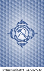 sickle and hammer icon inside blue emblem with geometric pattern.