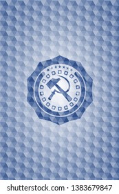 sickle and hammer icon inside blue emblem with geometric pattern background.