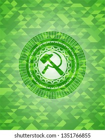 sickle and hammer icon inside green emblem with triangle mosaic background