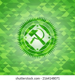 ícono de hoz y martillo dentro del emblema verde con fondo de mosaico. 