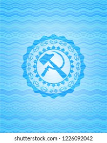 sickle and hammer icon inside light blue water badge.