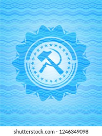 sickle and hammer icon inside light blue water wave emblem.