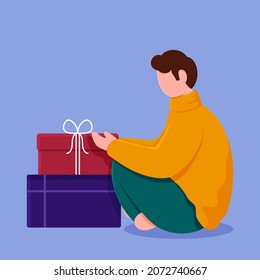 Side View Of Faceless Young Man Sitting With Gift Boxes On Blue Background.