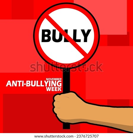 A sign prohibiting bullying is being held in a hand, with bold text on red background to commemorate Anti-Bullying Week on November