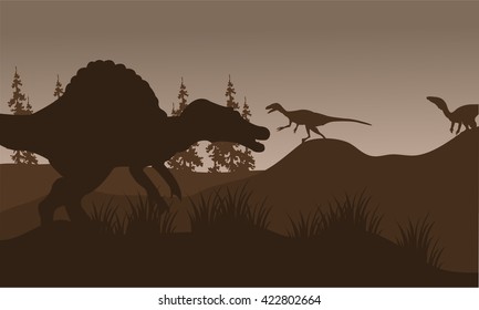 Silhouete of spinosaurus and eoraptor in hills with brown backgrounds