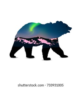 Silhouette of bear with green northern lights above mountains.