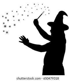 Silhouette of a bearded wizard in cloak with pointed hat creating magic 