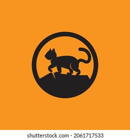 silhouette of a black cat standing on the rocks.