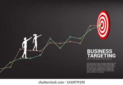 silhouette of businessman and businesswoman point to dartboard on line graph to center of dartboard. Business Concept of targeting and customer.route to success.