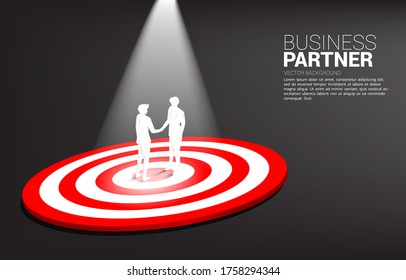 Silhouette of businessman handshake on center of dartboard. business concept of teamwork and championship. win the market target