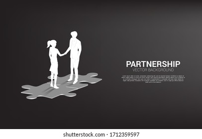 Silhouette of businessman handshake on jigsaw. Concept of team work  partnership and cooperation.