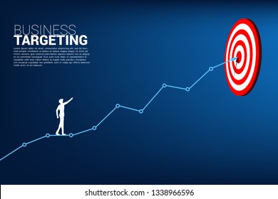 silhouette of businessman point to dartboard on line graph to center of dartboard. Business Concept of targeting and customer.route to success.