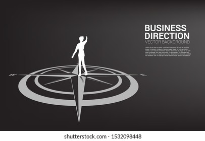 Silhouette of businessman standing at center of compass on floor and point forward. Concept of career path and business direction.