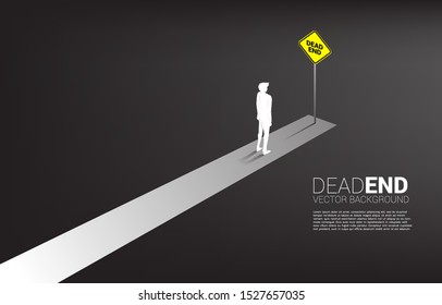 Silhouette businessman standing at the end of road with dead end signage  . Concept of wrong decision in business or end of career path.