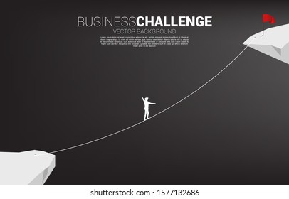 Silhouette of businessman walking on rope walk way to red flag.Concept for business risk and challenge in career path