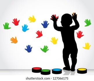 silhouette of a child draws on a white wall with colored hand prints